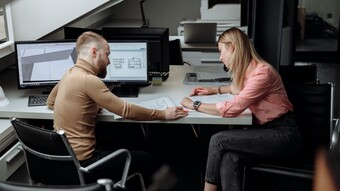 deux enseignants discutent autour d'un bureau et d'un ordinateur